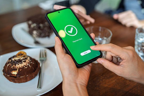 Phone showing payment sent at a cafe table