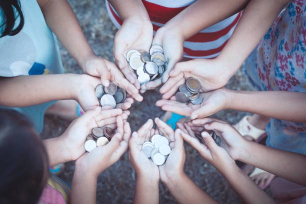 Children's hands holding coins in a circle